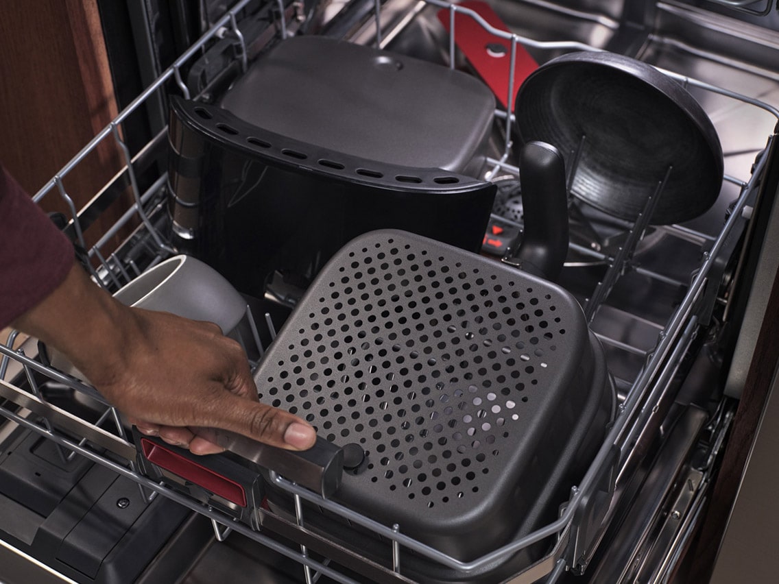 Lähikuva AEG-astianpesukoneen muunneltavasta sisustuksesta. Kone on täytetty kulhoilla ja airfryer-korilla havainnollistamaan laitteen tilavuutta.